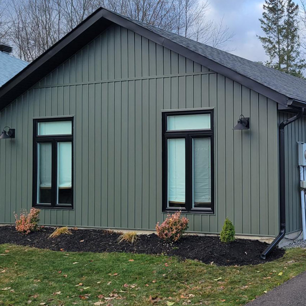 An Ontario home with dark green siding and black-framed windows.